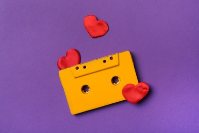 Music cassette and red hearts on purple background, flat lay. Listening love song