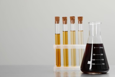 Photo of Laboratory glassware with brown liquids on light background. Space for text