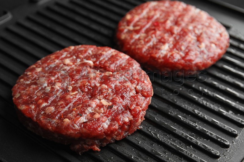 Raw meat cutlets for burger on grill, closeup
