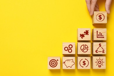 Top view of woman and wooden cubes with different images on yellow background. Space for text