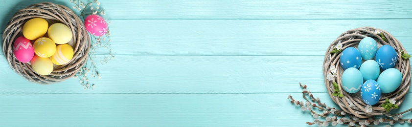 Image of Flat lay composition with colorful Easter eggs on light blue wooden table, space for text. Horizontal banner design