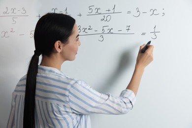 Photo of Young teacher explaining mathematics at whiteboard in classroom
