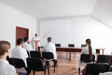 Photo of Doctor giving lecture in conference room with projection screen