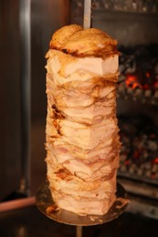 Photo of Vertical rotisserie with roasted meat in restaurant kitchen