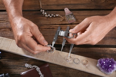 Male jeweler evaluating diamond bracelet in workshop, closeup view