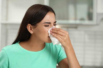 Young woman suffering from allergy in kitchen