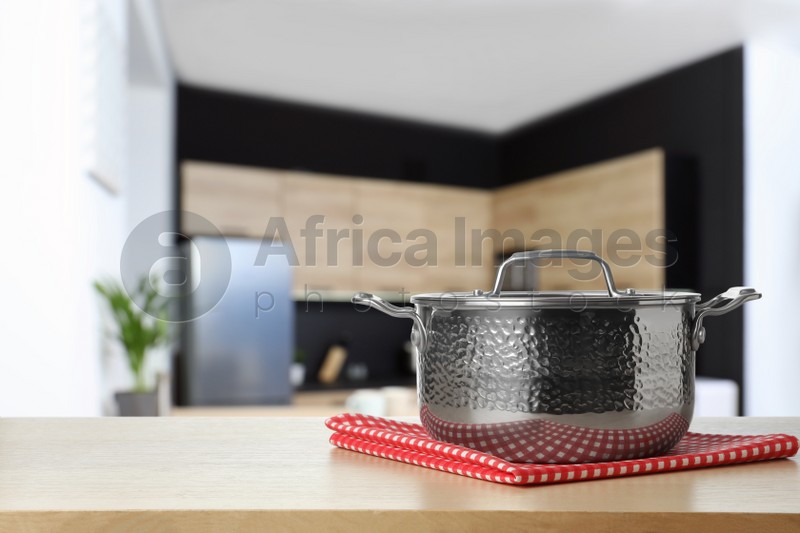 Towel and pot on wooden table in kitchen. Space for text