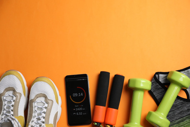 Flat lay composition with fitness equipment and smartphone on orange background, space for text