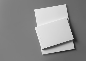 Brochures with blank covers on light grey background, top view. Space for text