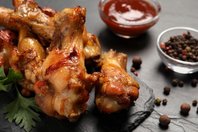 Photo of Delicious fried chicken wings on black table, closeup