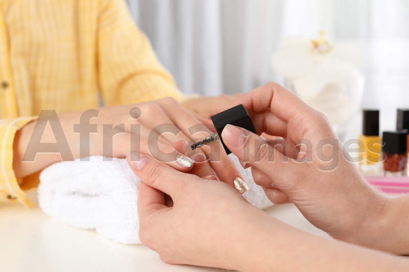 Manicurist painting client's nails with polish in salon, closeup