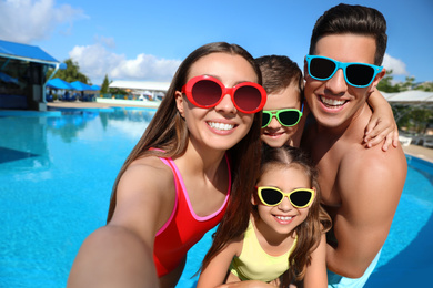 Happy family taking selfie near swimming pool.  Summer vacation