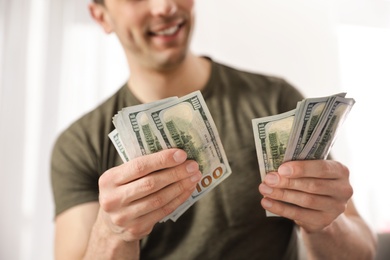 Young man counting money on blurred  background, closeup