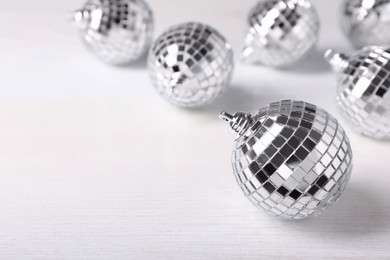Shiny disco balls on white wooden background. Space for text