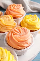 Tasty colorful cupcakes with cream on marble stand, closeup