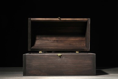 Empty treasure chest on wooden table against black background