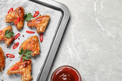 Photo of Tray with delicious fried chicken wings on light gray marble table, flat lay. Space for text