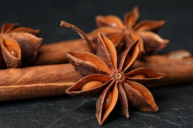 Aromatic anise stars and cinnamon sticks on black table, closeup