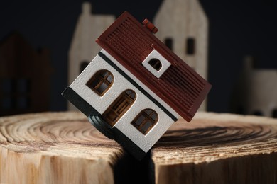 House model in cracked wooden stump depicting earthquake disaster, closeup