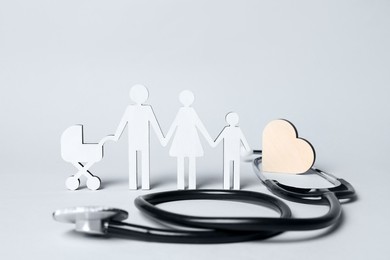 Photo of Figures of family stainding near stethoscope on white background. Insurance concept