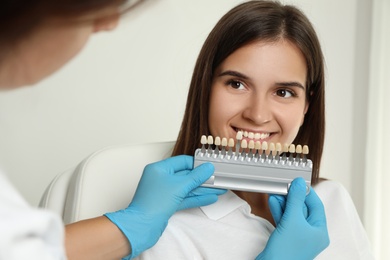 Doctor checking young woman's teeth color in clinic. Cosmetic dentistry