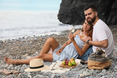 Young couple having picnic on beach near sea. Space for text