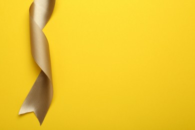Photo of Beautiful ribbon on yellow background, top view. Space for text