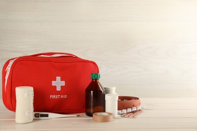 First aid kit on white wooden table, space for text