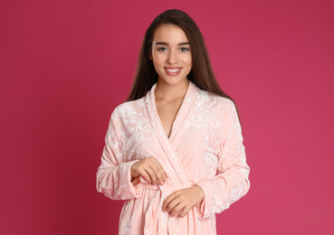 Young woman in bathrobe on crimson background