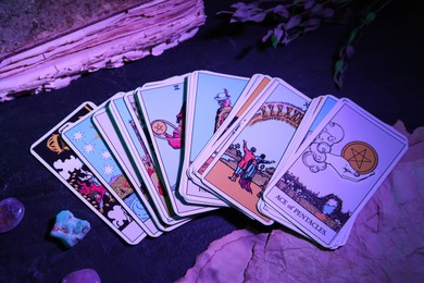 Tarot cards and old book on dark table, color toned
