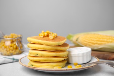 Tasty corn pancakes with sauce served on light grey table