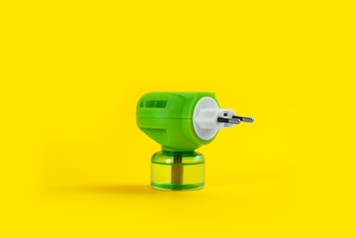 Electric vaporizer with insect repellent liquid on yellow background