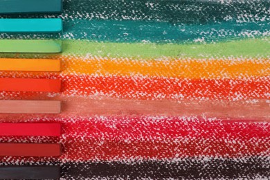 Colorful pastel chalks on abstract painting, flat lay. Drawing materials