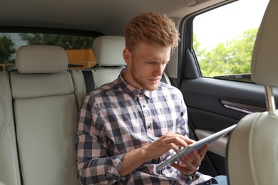 Attractive young man using tablet in luxury car