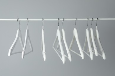 White clothes hangers on metal rail against light background