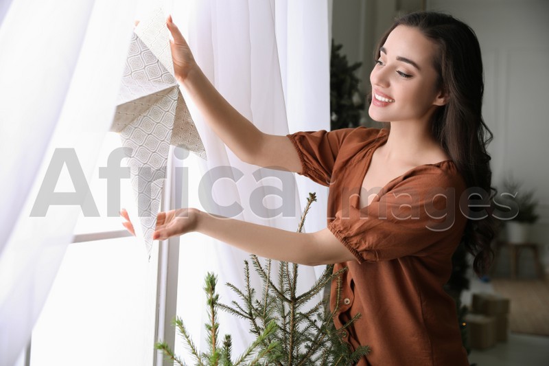 Woman putting decorative star on window at home