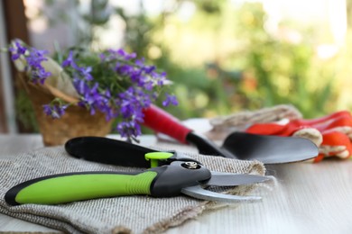 Photo of Secateurs, flowers and other gardening tools on white wooden table