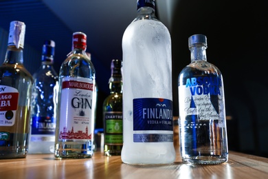 MYKOLAIV, UKRAINE - SEPTEMBER 24, 2019: Bottles of global vodka brands on wooden counter in bar