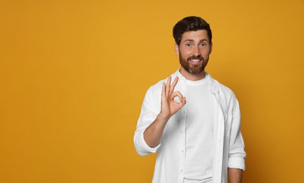 Photo of Bearded man showing ok gesture on orange background. Space for text