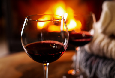 Glasses of wine, knitwear and blurred fireplace on background