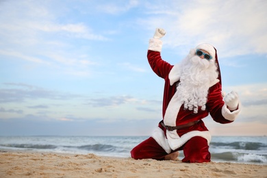 Santa Claus having fun on beach, space for text. Christmas vacation