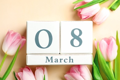 Wooden block calendar with date 8th of March and tulips on beige background, flat lay. International Women's Day