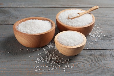 Photo of Bowls of natural sea salt on grey wooden table