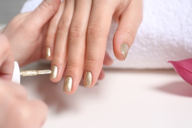 Manicurist painting client's nails with polish in salon, closeup