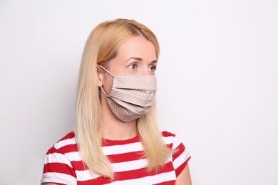 Woman wearing handmade cloth mask on white background. Personal protective equipment during COVID-19 pandemic