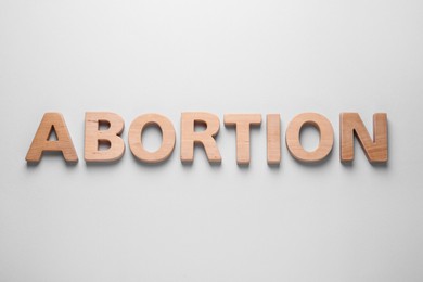 Word Abortion made of wooden letters on light grey background, flat lay