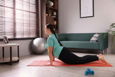 Overweight woman doing exercise on yoga mat at home