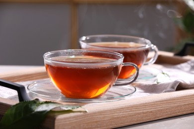 Photo of Aromatic hot tea in glass cups on light grey table indoors, closeup