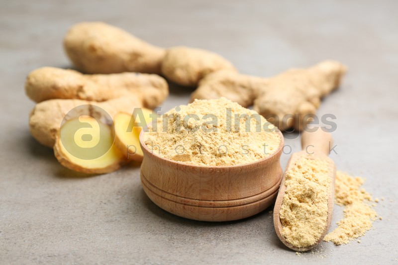 Photo of Dry ginger powder and fresh root on grey table