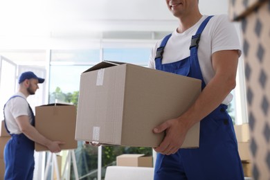 Moving service employees with cardboard boxes in room, closeup